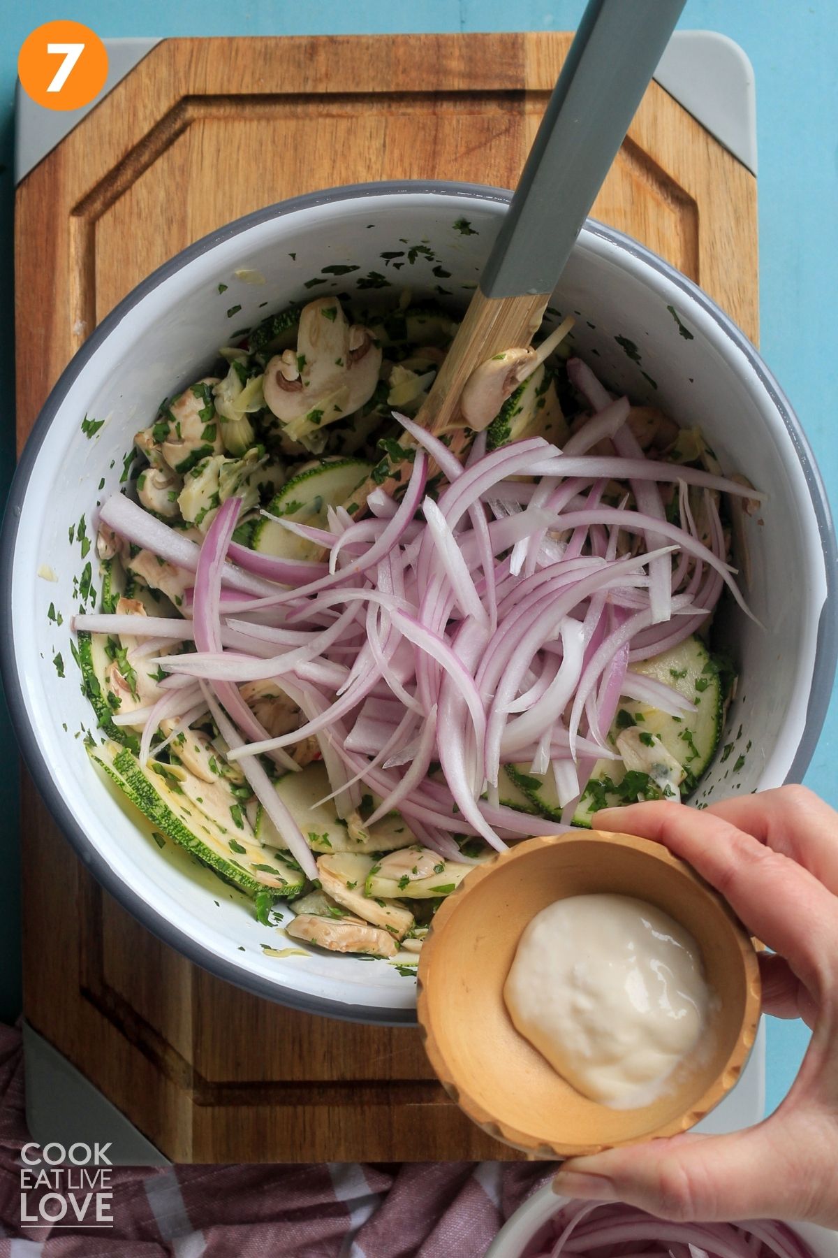 Onions added to the vegan ceviche and a hand holding a dish of mayo. 