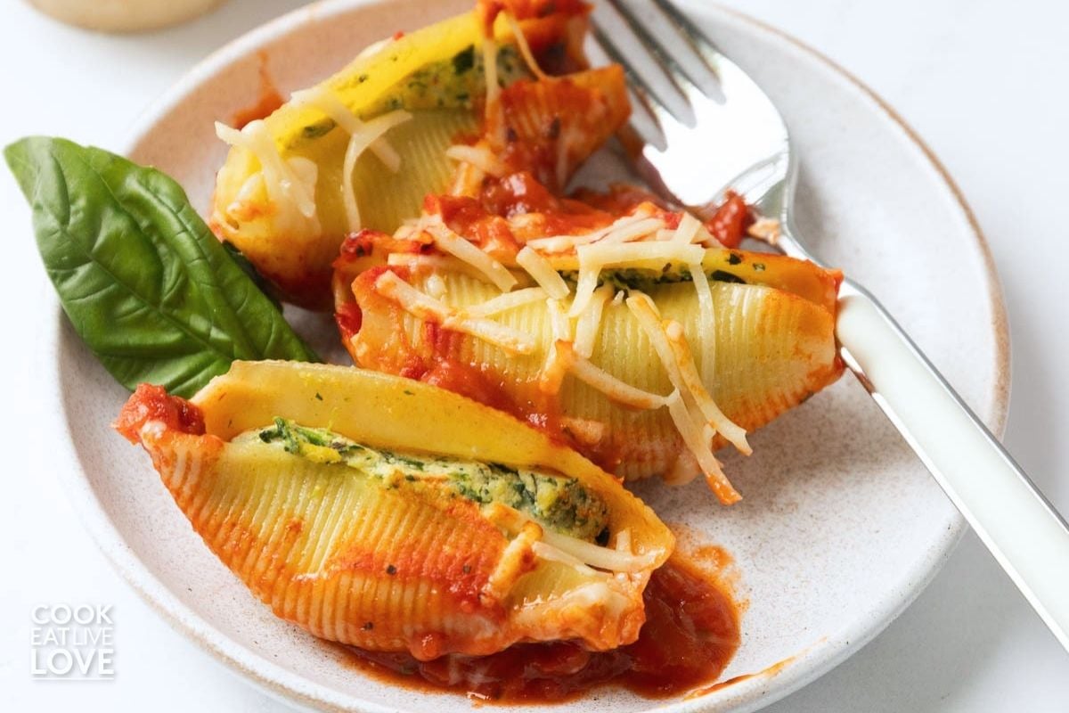 A plate of vegan stuffed shells with a fork resting to the side. 