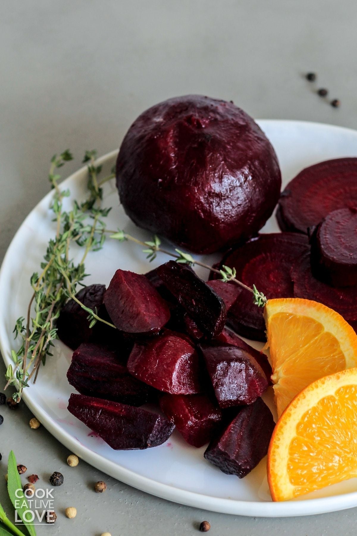 Roasted beets on a plate with orange slices and herbs. 