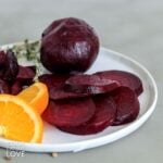 Sliced and whole roasted beets on a plate.