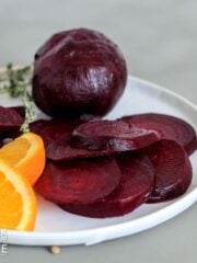 Sliced and whole roasted beets on a plate.