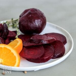 Sliced and whole roasted beets on a plate.