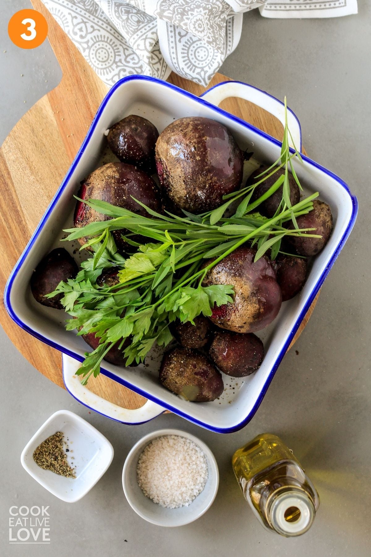 Herbs added to top of whole beets in baking dish