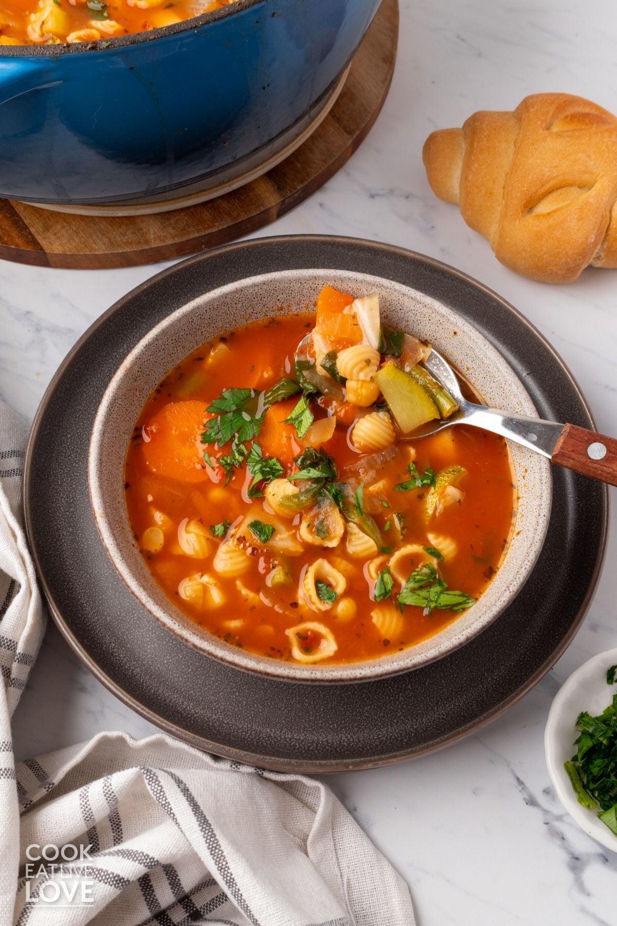 A bowl of vegan minestrone soup on a table in front of the pot. 