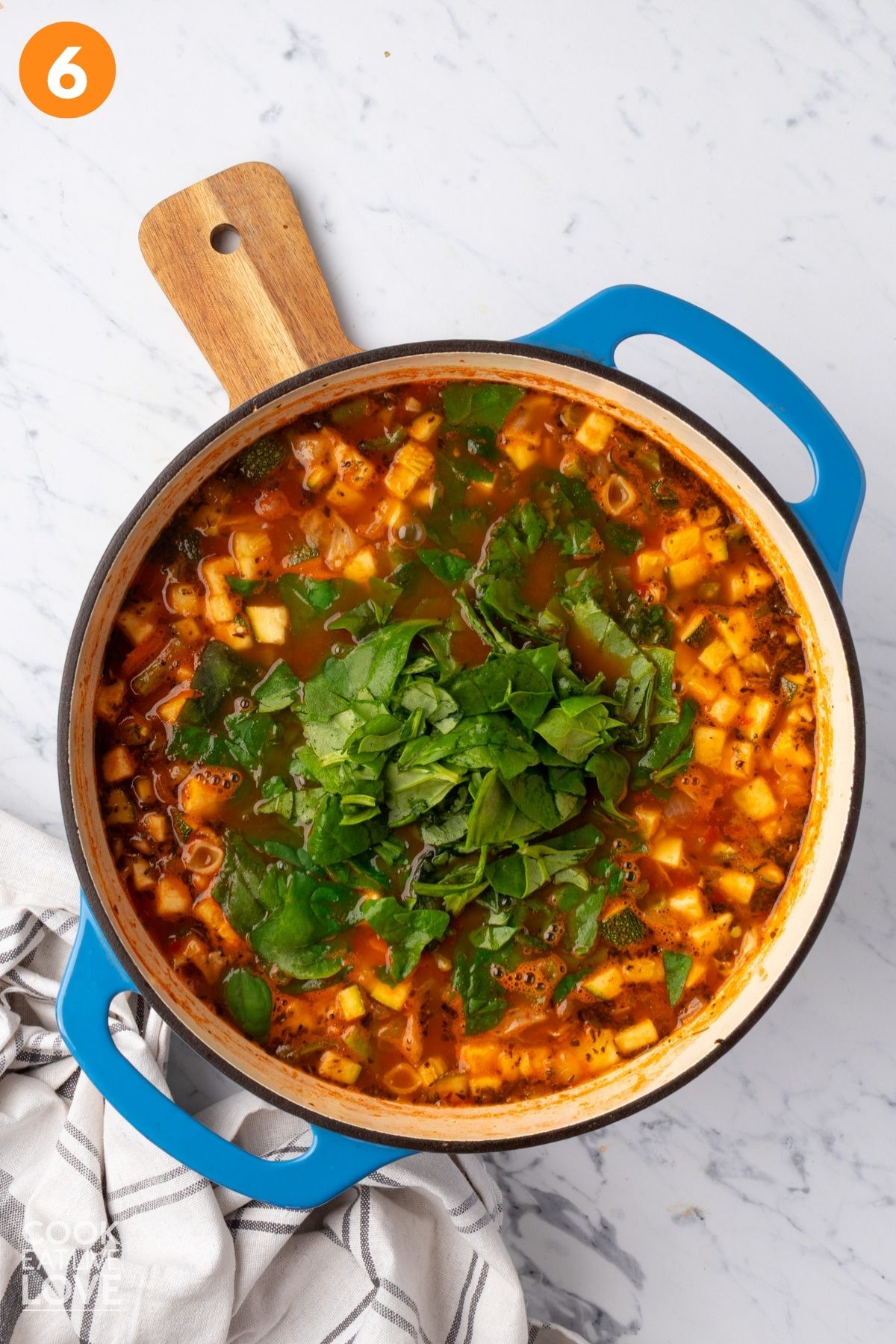 Spinach added to the pot of vegan minestrone soup. 