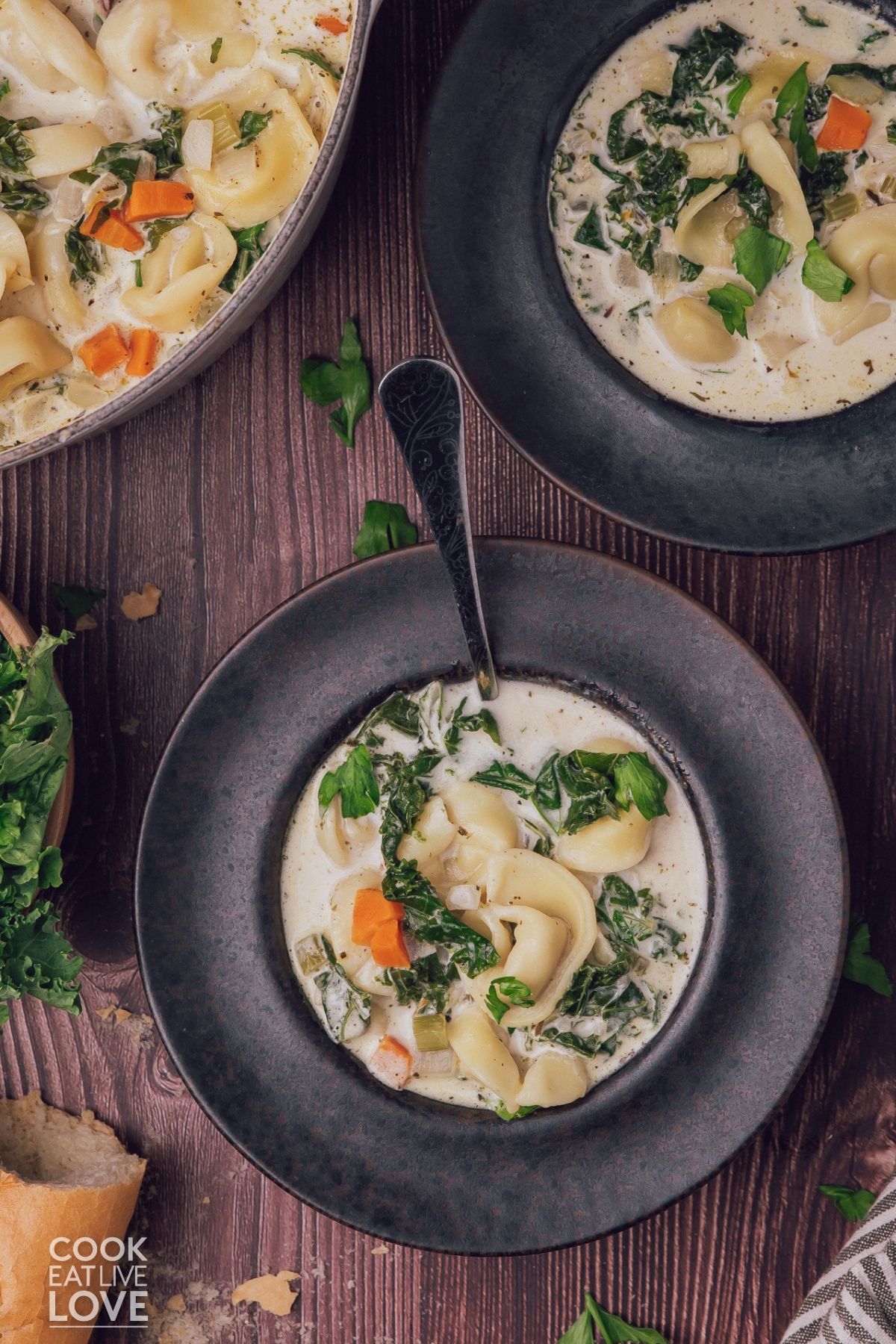 Bowls and a pot of cheese tortellini soup on a table. 