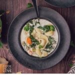 A bowl of cheese tortellini soup with a spoon resting in the bowl.